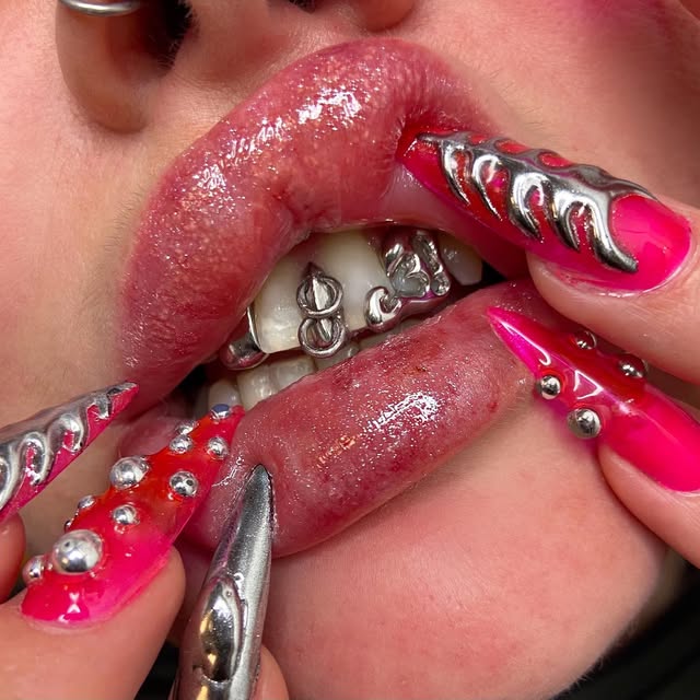 Doigts aux ongles roses dévoilant des tooth gems argentées